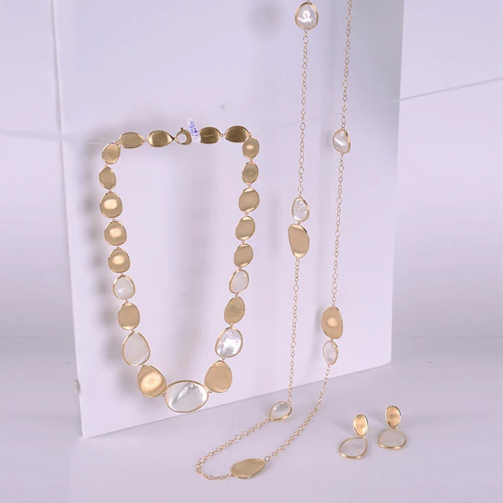 Gold and pearl jewelry set featuring a necklace, chain, and earrings, displayed before background removal.