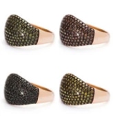 Four gold rings with varied gemstone colors, including black, green, brown, and yellow, arranged in a grid.