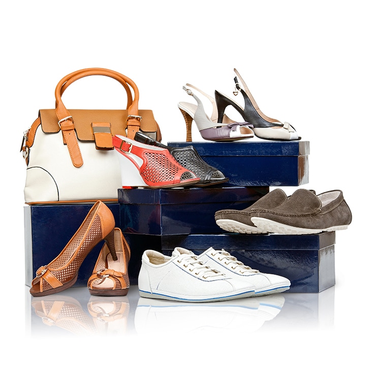 Assorted shoes and handbag displayed with intricate reflection shadow on a glossy white background.