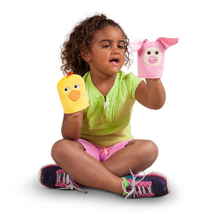 A young girl playing with yellow duck and pink pig hand puppets, enhanced with a simple natural shadow for realism.