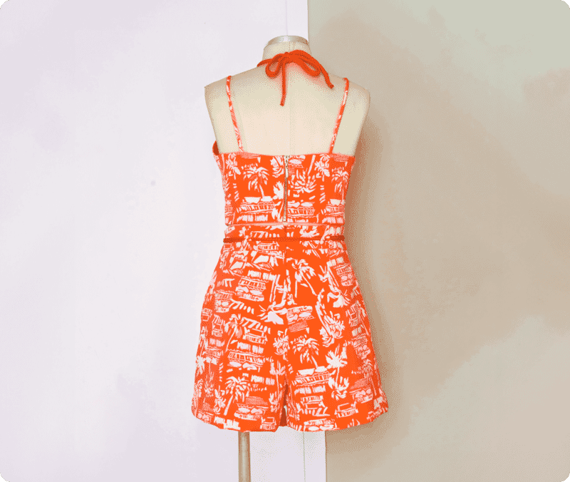 Original mannequin photo of an orange tropical print romper before ghost mannequin editing and background removal.