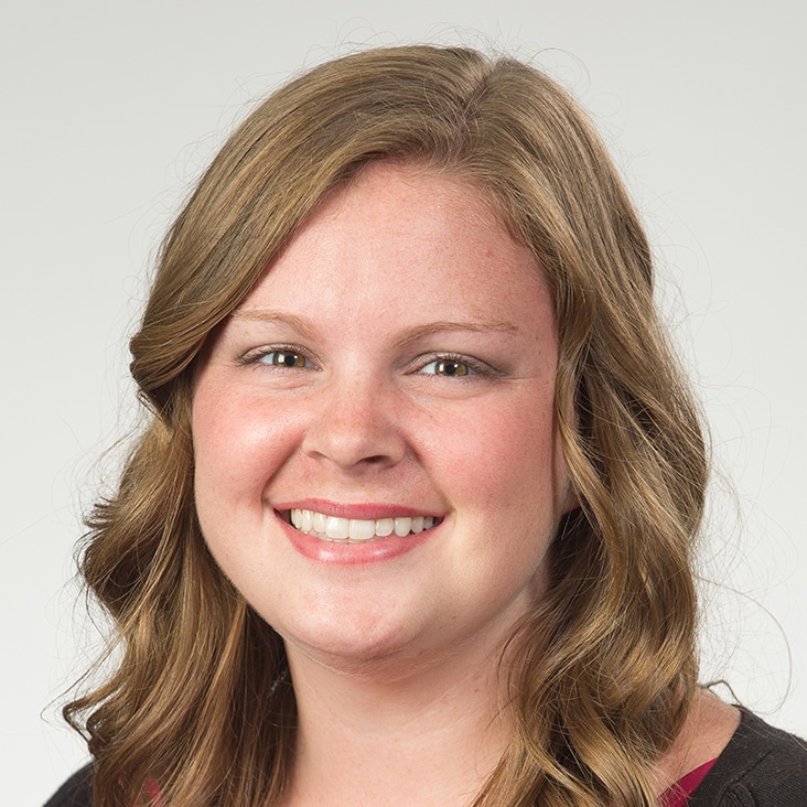 Close-up portrait of a woman with natural complexion and wavy hair, shown before beauty airbrushing edits.