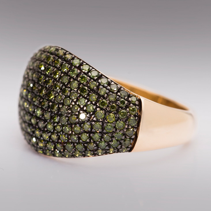 Gold ring adorned with green gemstones, shown with a polished surface after camera reflection removal.