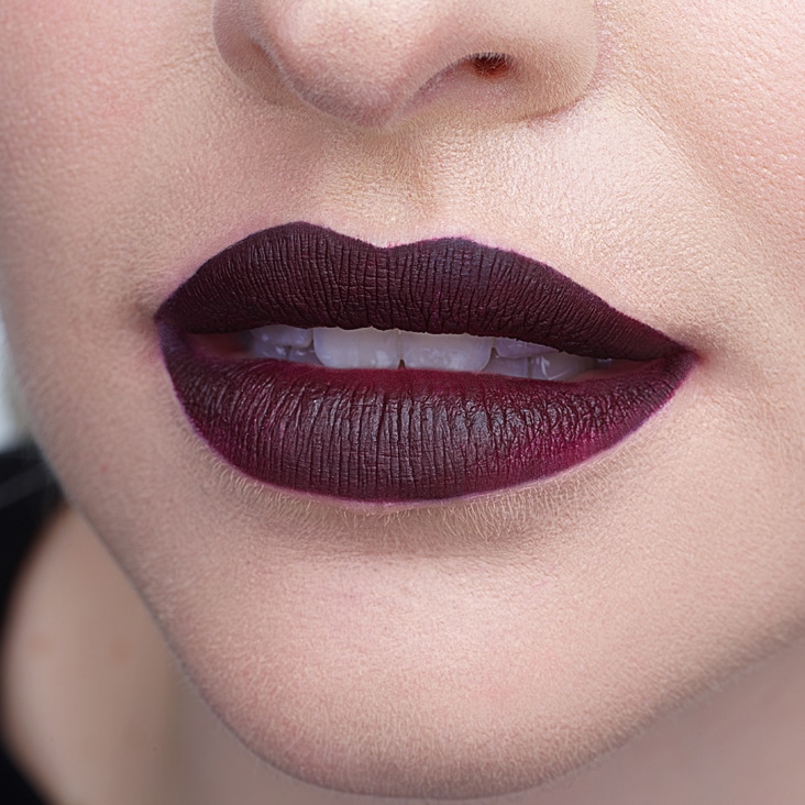 Close-up of retouched lips with deep purple lipstick, showcasing smooth skin and precision beauty airbrushing techniques.