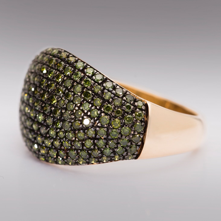 Gold ring with green gemstones featuring removed camera reflections for enhanced jewelry presentation.