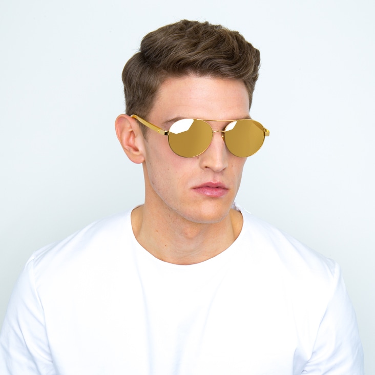 Man wearing gold sunglasses with camera reflections removed for polished eyewear presentation.