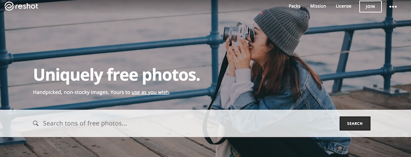 Reshot homepage offering uniquely free, handpicked photos with search bar and woman photographing
