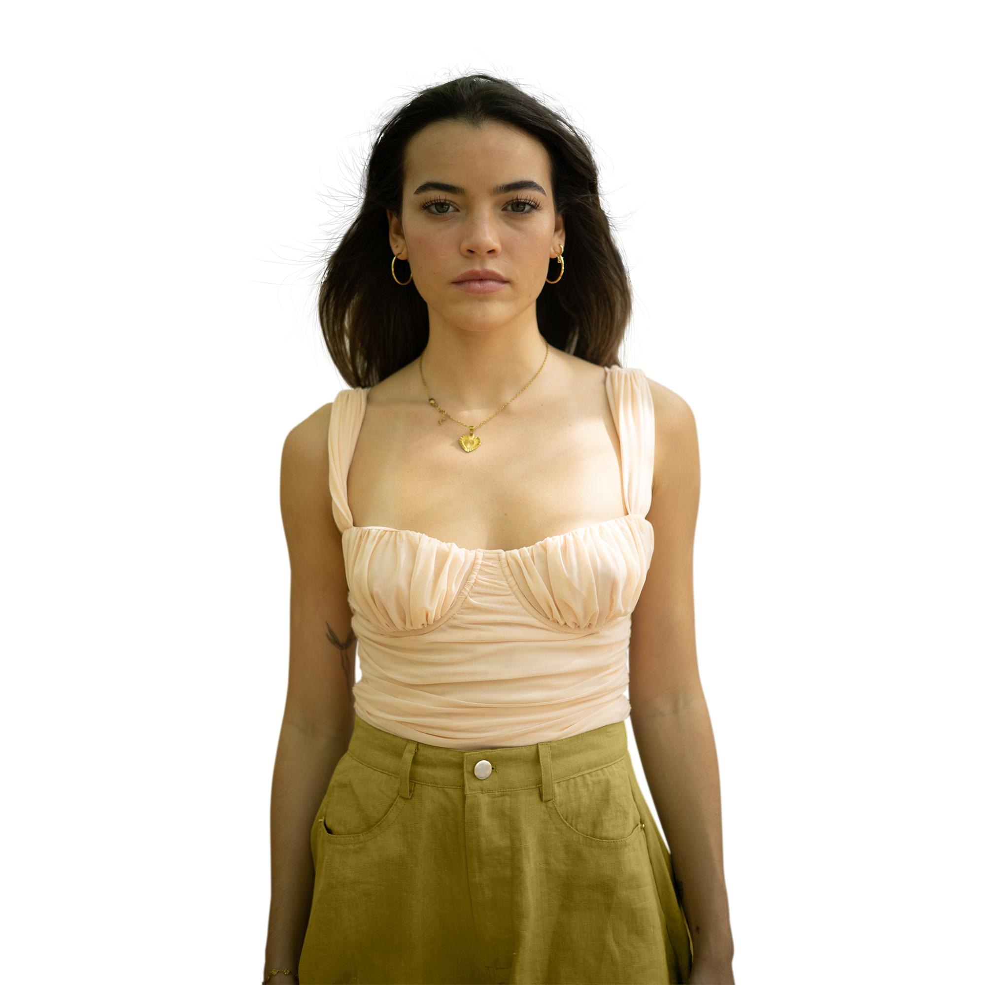 Portrait of woman in light top and green pants on white background, with shadows removed.