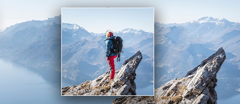 Hiker on mountain peak with background partially masked for editing purposes.