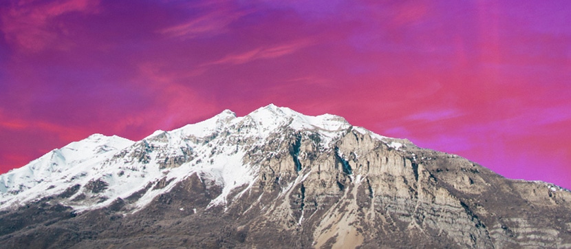Snow-capped mountain against a vivid, color-enhanced pink and purple sky.