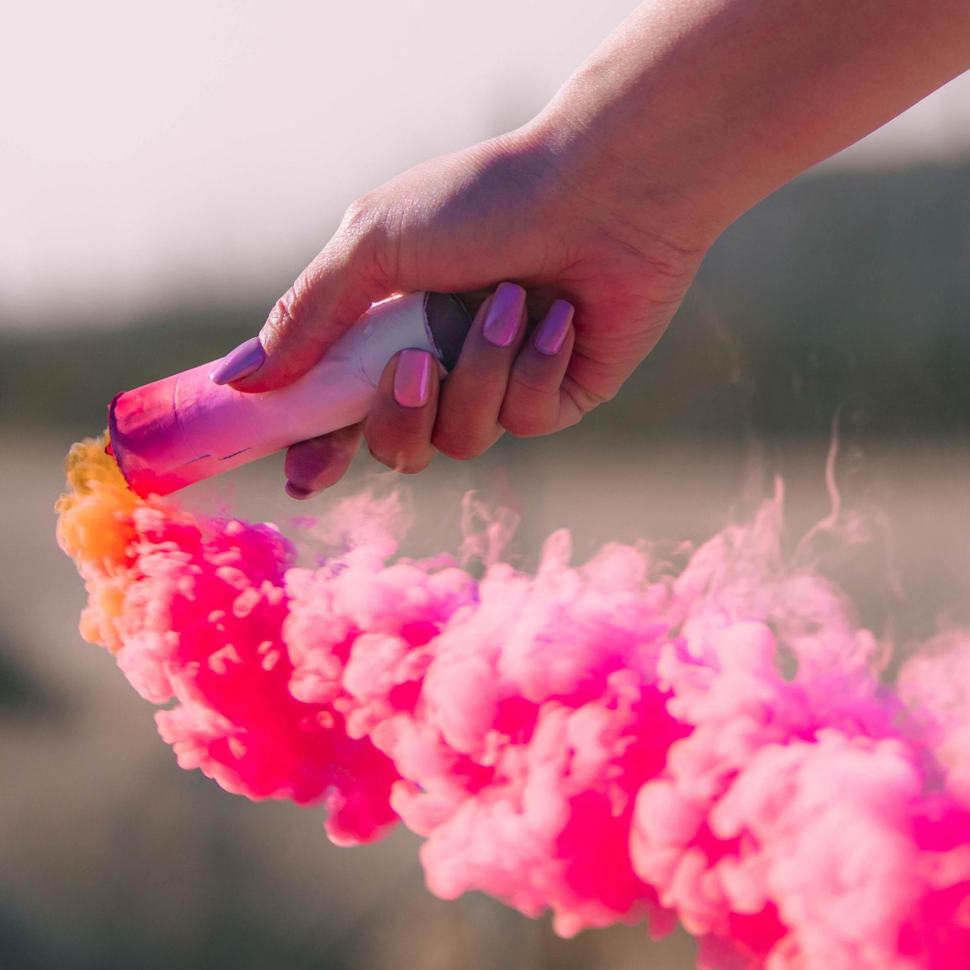 Photographer creating dramatic effect with pink smoke outdoors