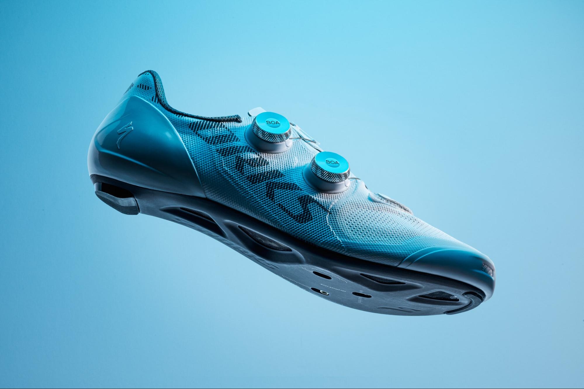 Close-up of a blue cycling shoe with BOA dials, suspended against a blue background.