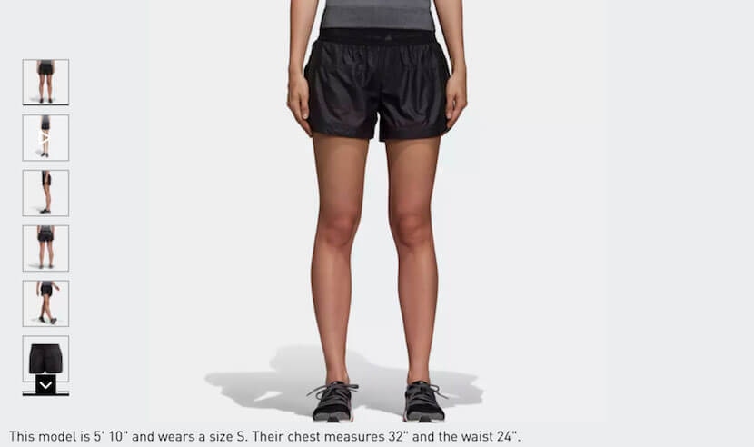 Adidas model wearing black athletic shorts, front view with size and fit details displayed below