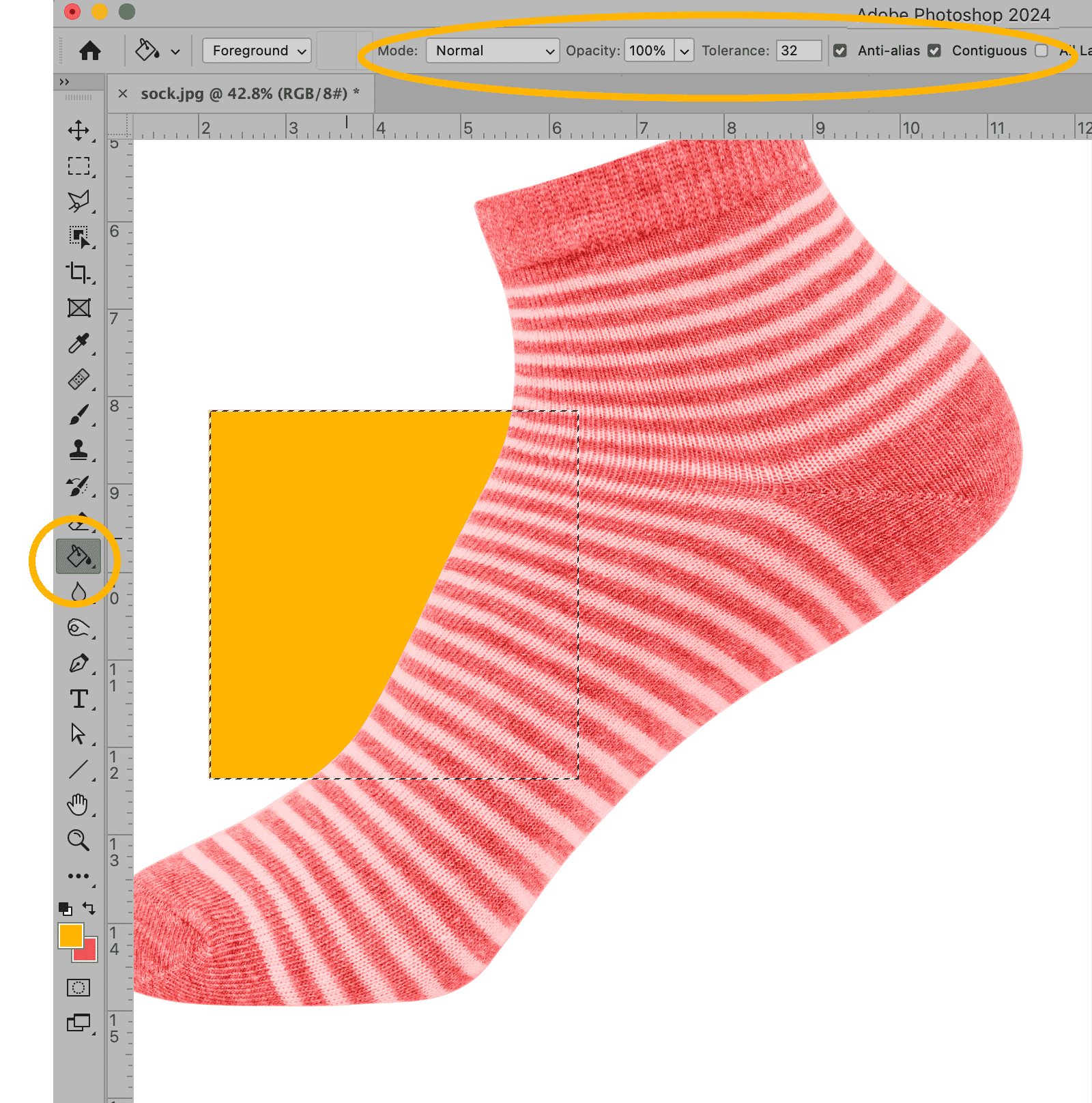 Photoshop interface showing the Paint Bucket Tool in use to fill a selected area on a striped sock image with yellow color.