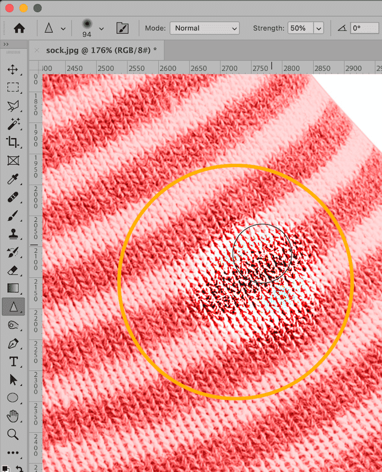 Zoomed-in view of a red striped sock in Photoshop with the Sharpen Tool applied, showing enhanced texture details.