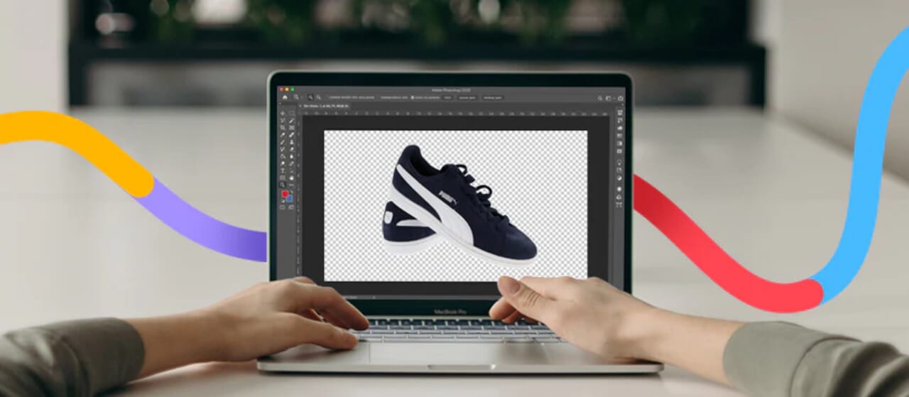Hands editing a black and white sneaker image on a laptop using Photoshop, with colorful design accents.