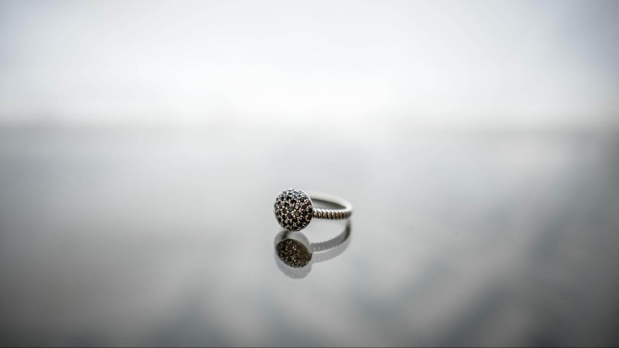 Minimalist diamond pavé ring displayed on a soft gradient reflective surface