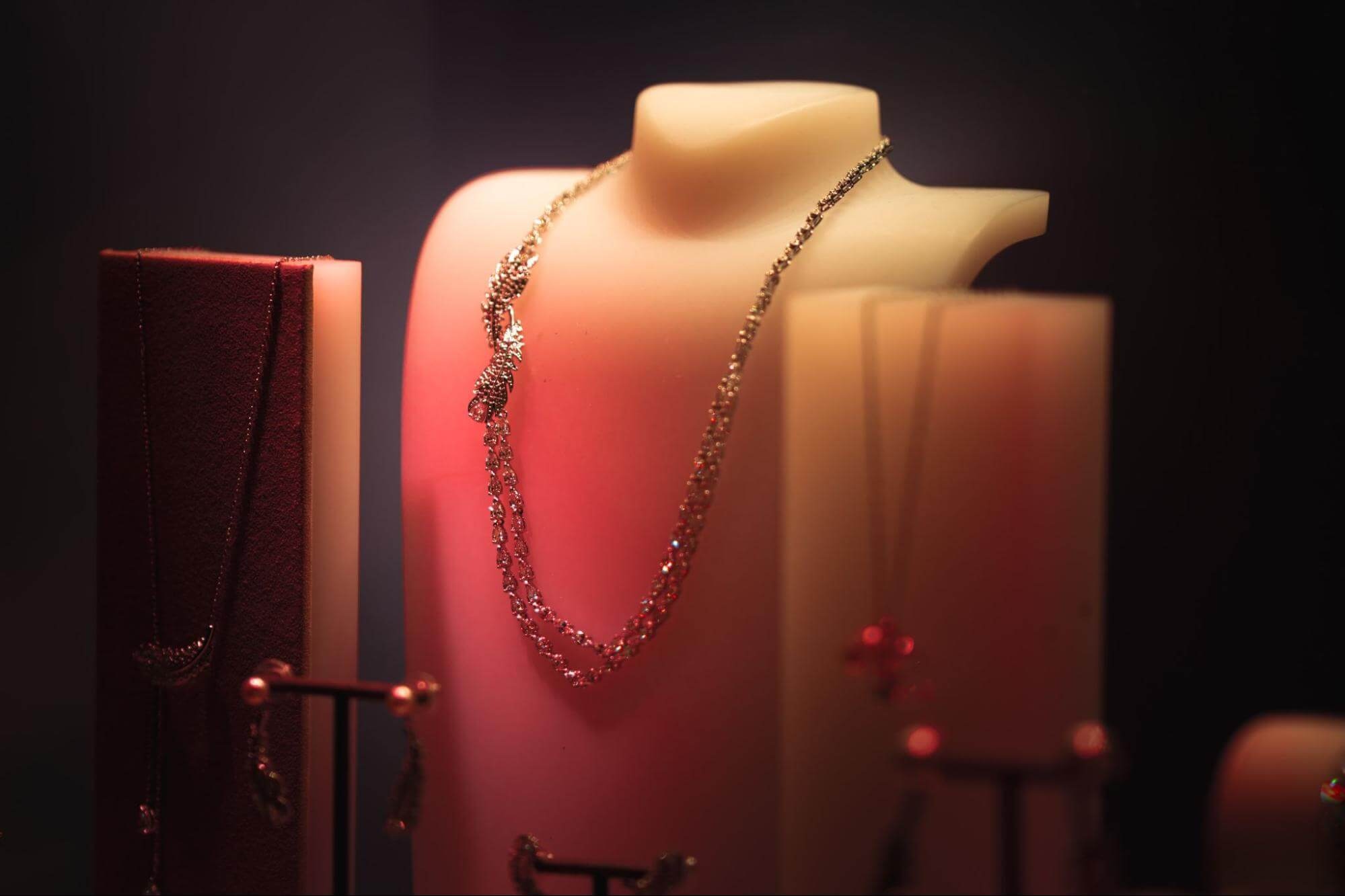 Gold necklace displayed on a mannequin with warm, dramatic lighting in a jewelry showcase