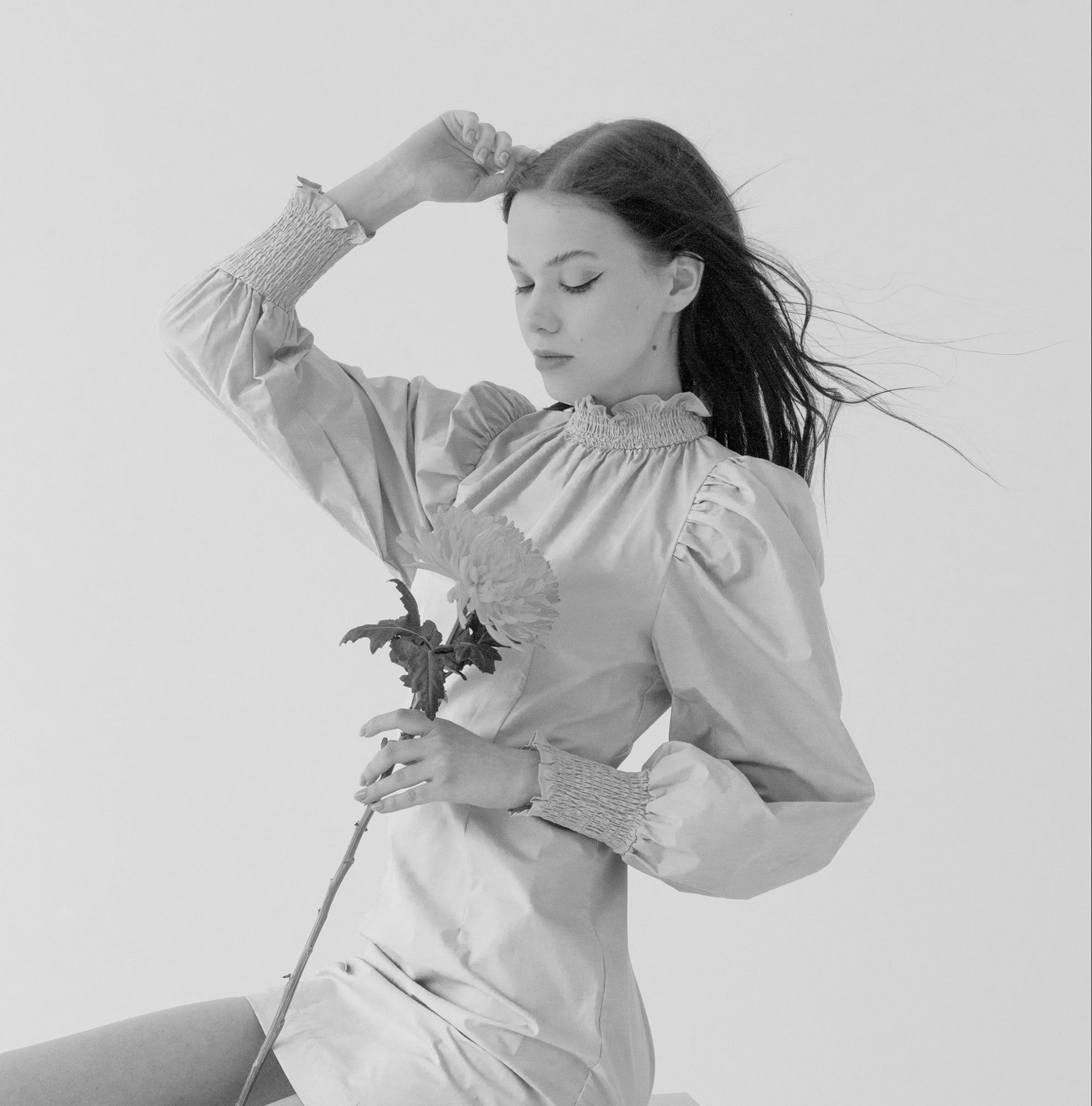 Black and white image of a woman holding a flower in grayscale mode for improved luminescence effect.