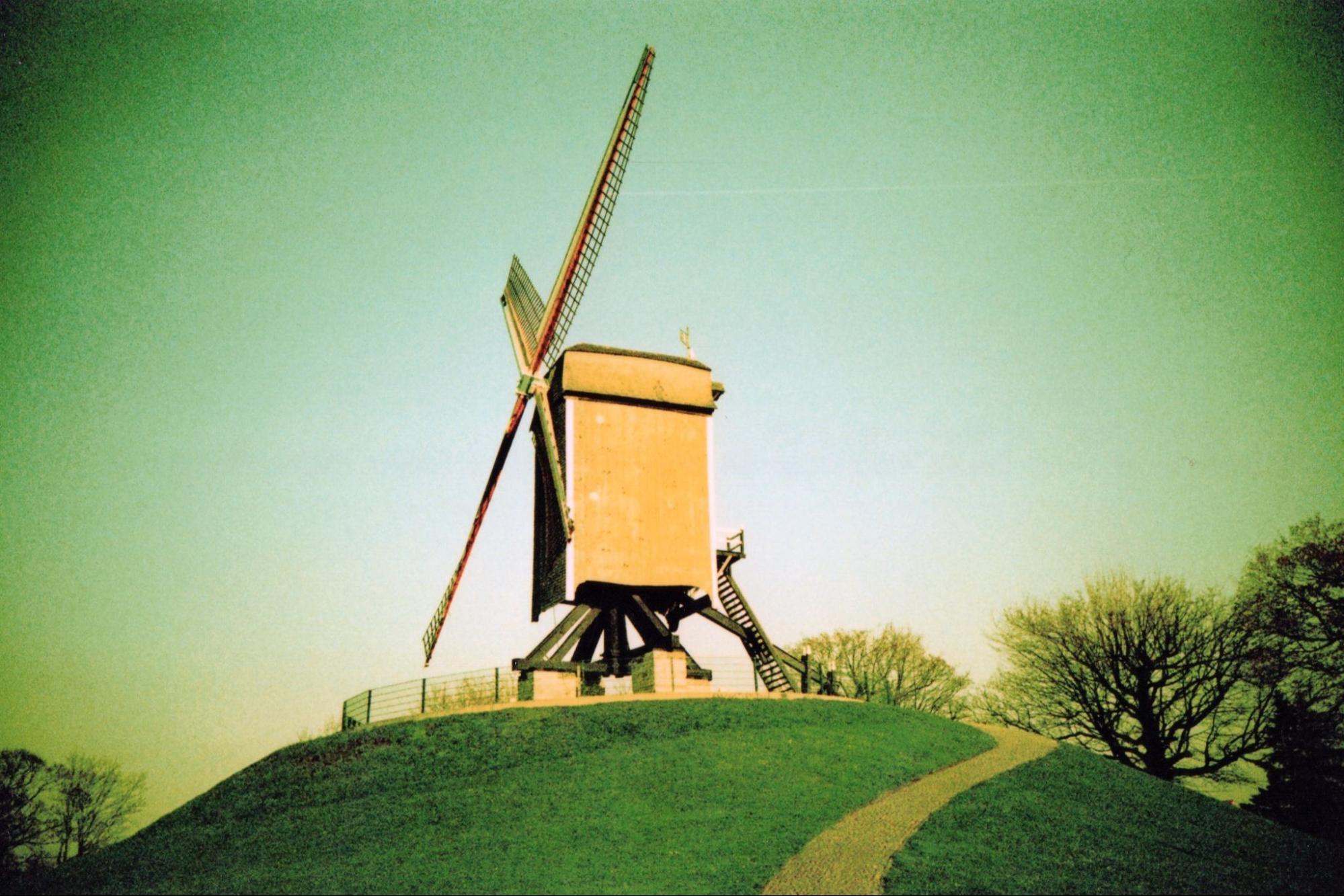 Vintage-style photo of a windmill on a hill with a green hue, emulating classic film photography effects.