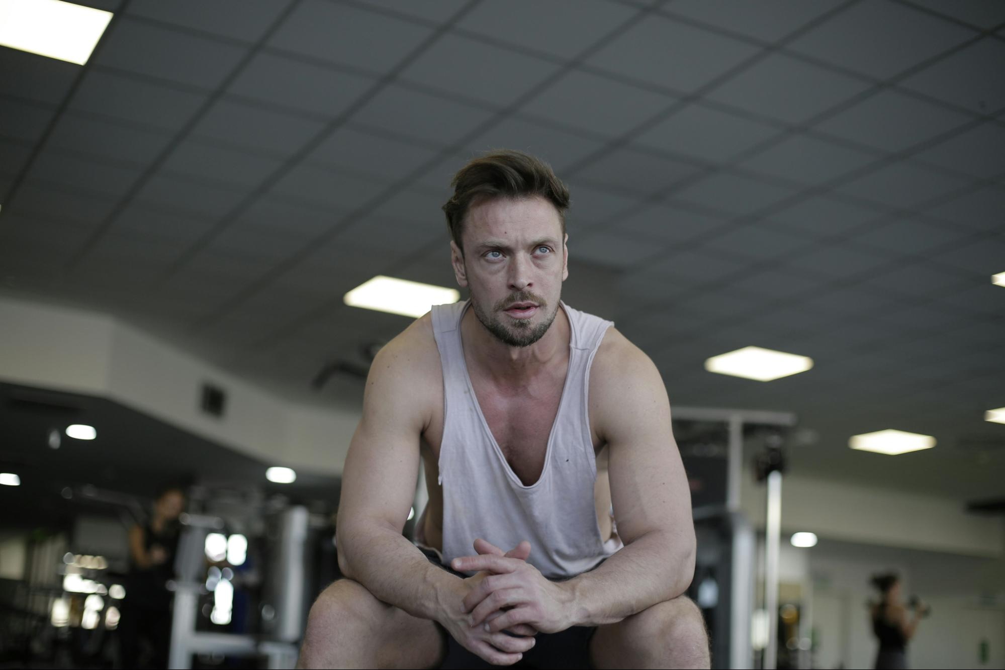 Male athlete seated in gym without corrected skin tones; before and after comparison.