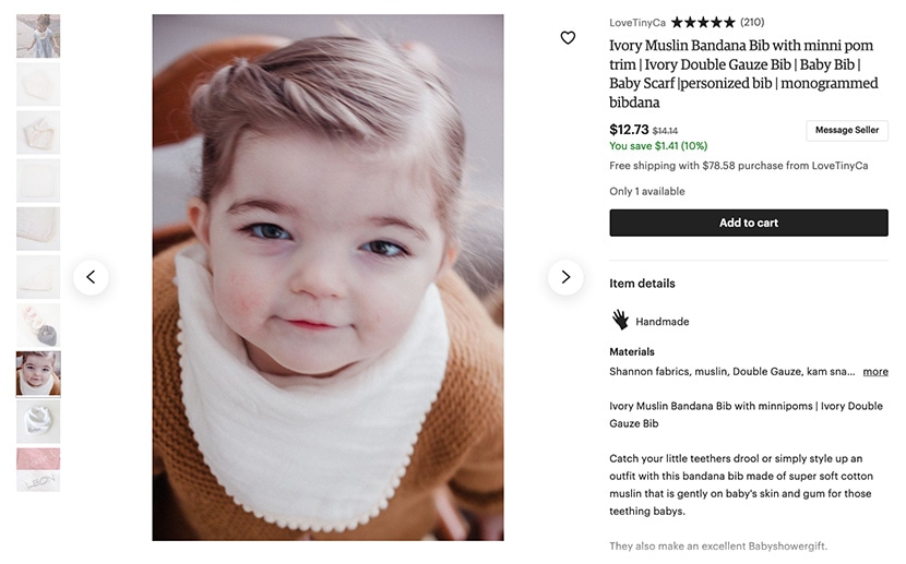 Etsy listing for a handmade ivory muslin bandana bib with pom trim, modeled by a young child, priced at $12.73.