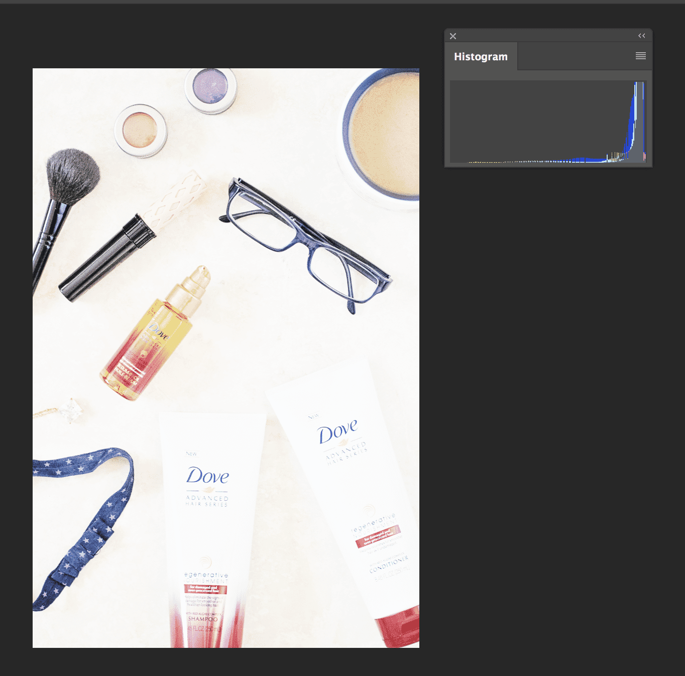 Flat lay of beauty products, glasses, and accessories with histogram for exposure analysis
