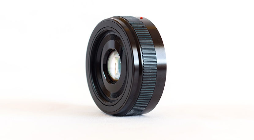 Close-up of a black camera lens on a white background for product photography.