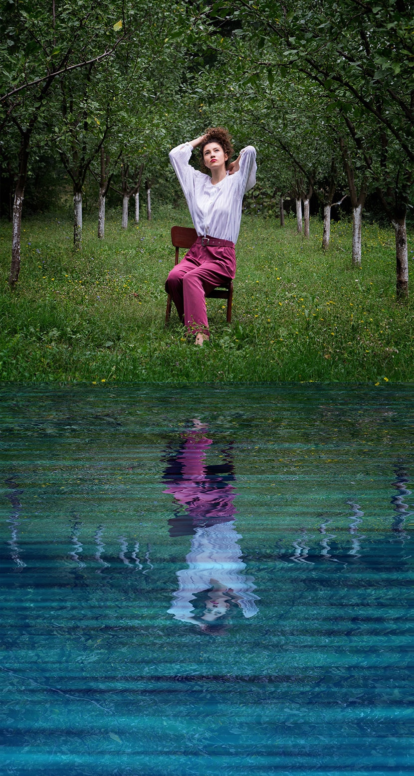 Outdoor portrait of a model with a realistic water reflection effect created in Photoshop, blending nature and mirror-like water.