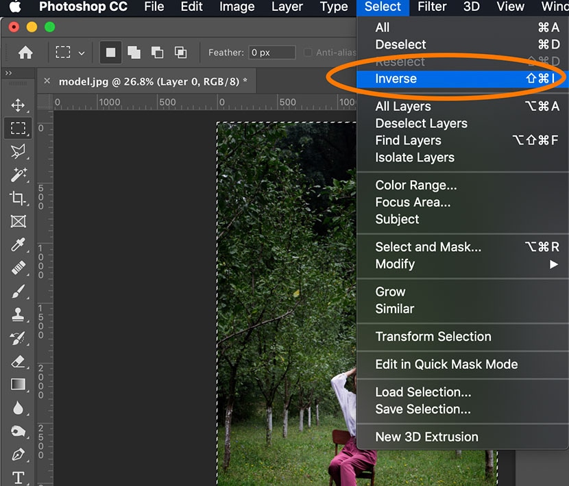 Selecting the Inverse option in Photoshop’s Select menu to modify the background around a model in an outdoor scene.