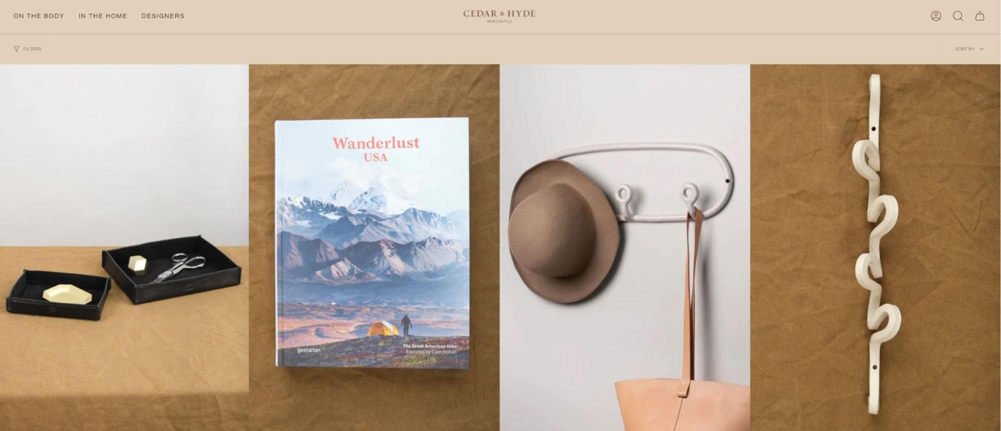 Display of curated home goods including a leather tray, mountain book, wall hooks, and hat holder from Cedar & Hyde Mercantile