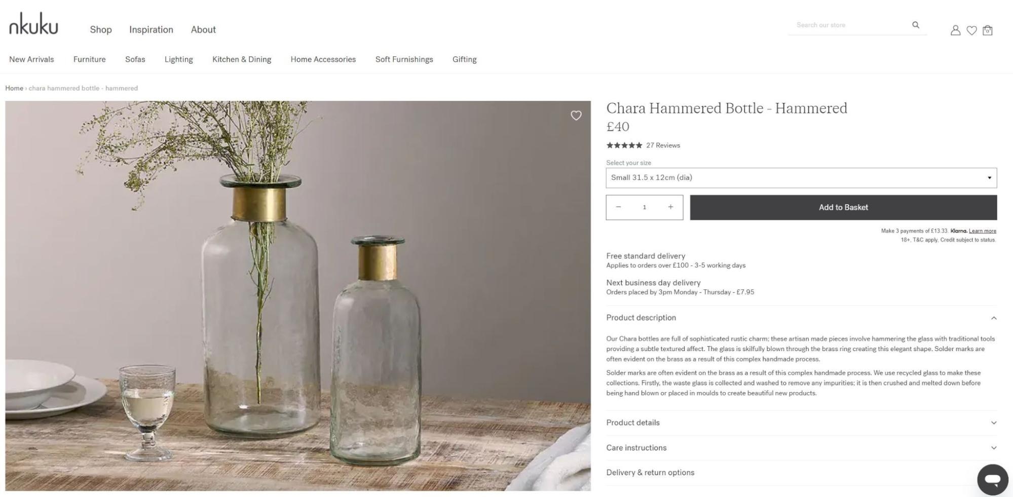 Nkuku Chara hammered glass bottle with brass neck detail, small size, on rustic wooden table