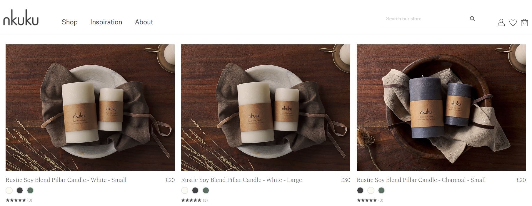 Nkuku rustic soy blend pillar candles in white and charcoal on a wooden surface with linen wrapping