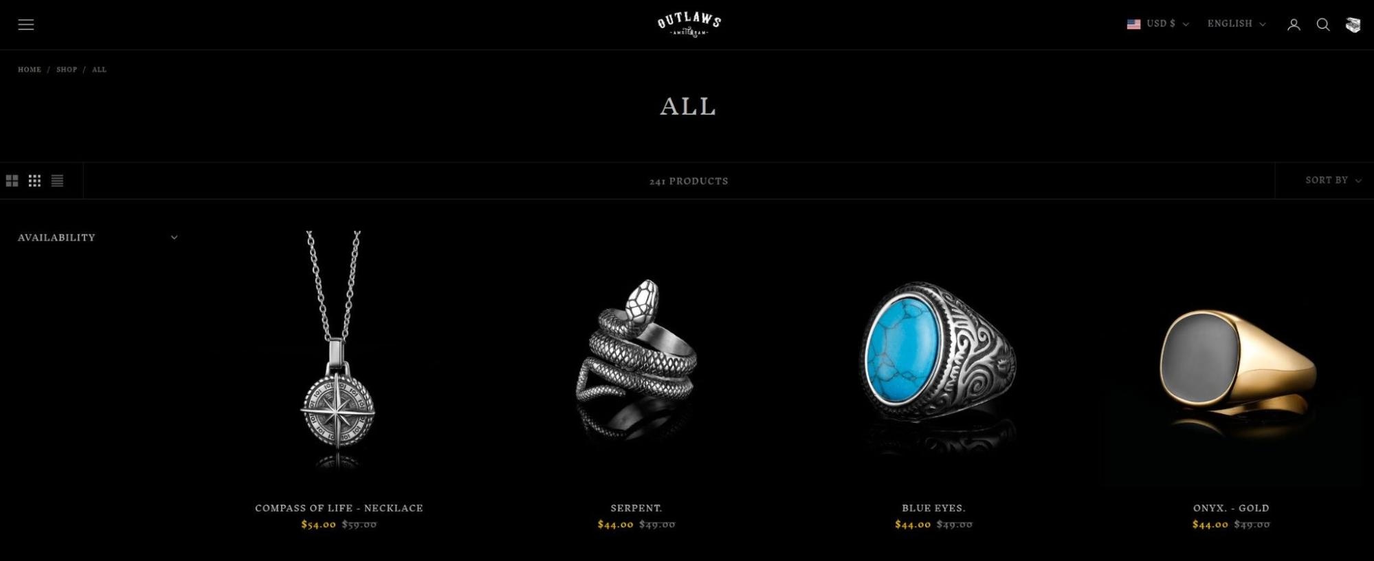 Outlaws Amsterdam jewelry collection featuring compass necklace, serpent ring, blue stone ring, and gold onyx ring