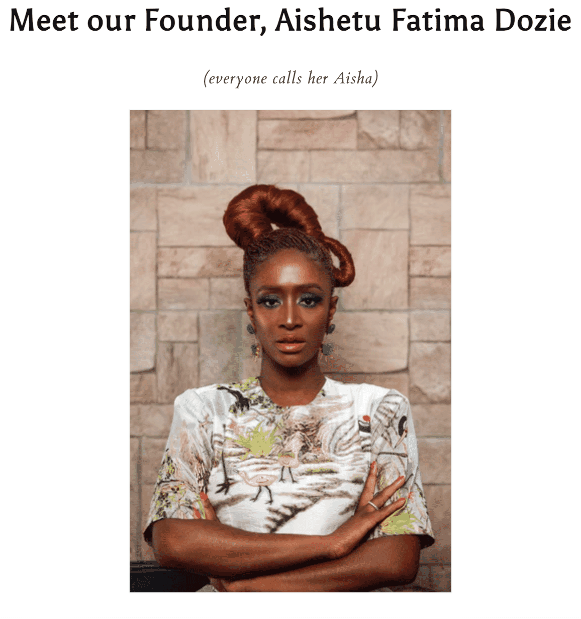 Aishetu Fatima Dozie, founder, with vibrant hairstyle and patterned top, standing against textured wall