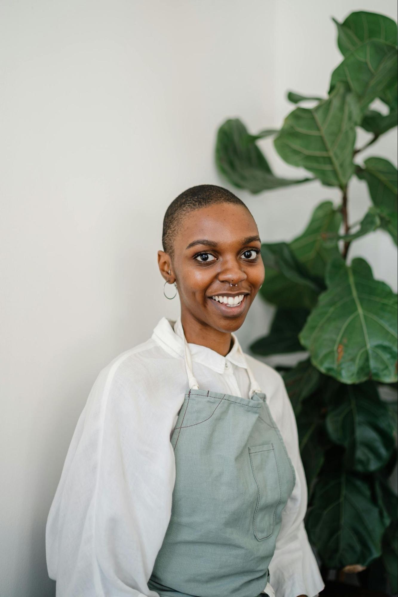 Smiling woman in apron with green plant background