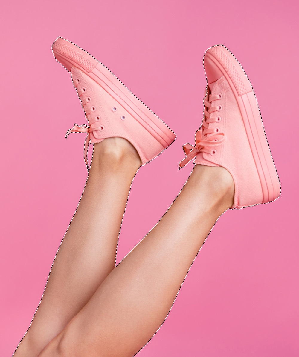 Close-up of pink sneakers with Photoshop marching ants selection outline on a pink background.
