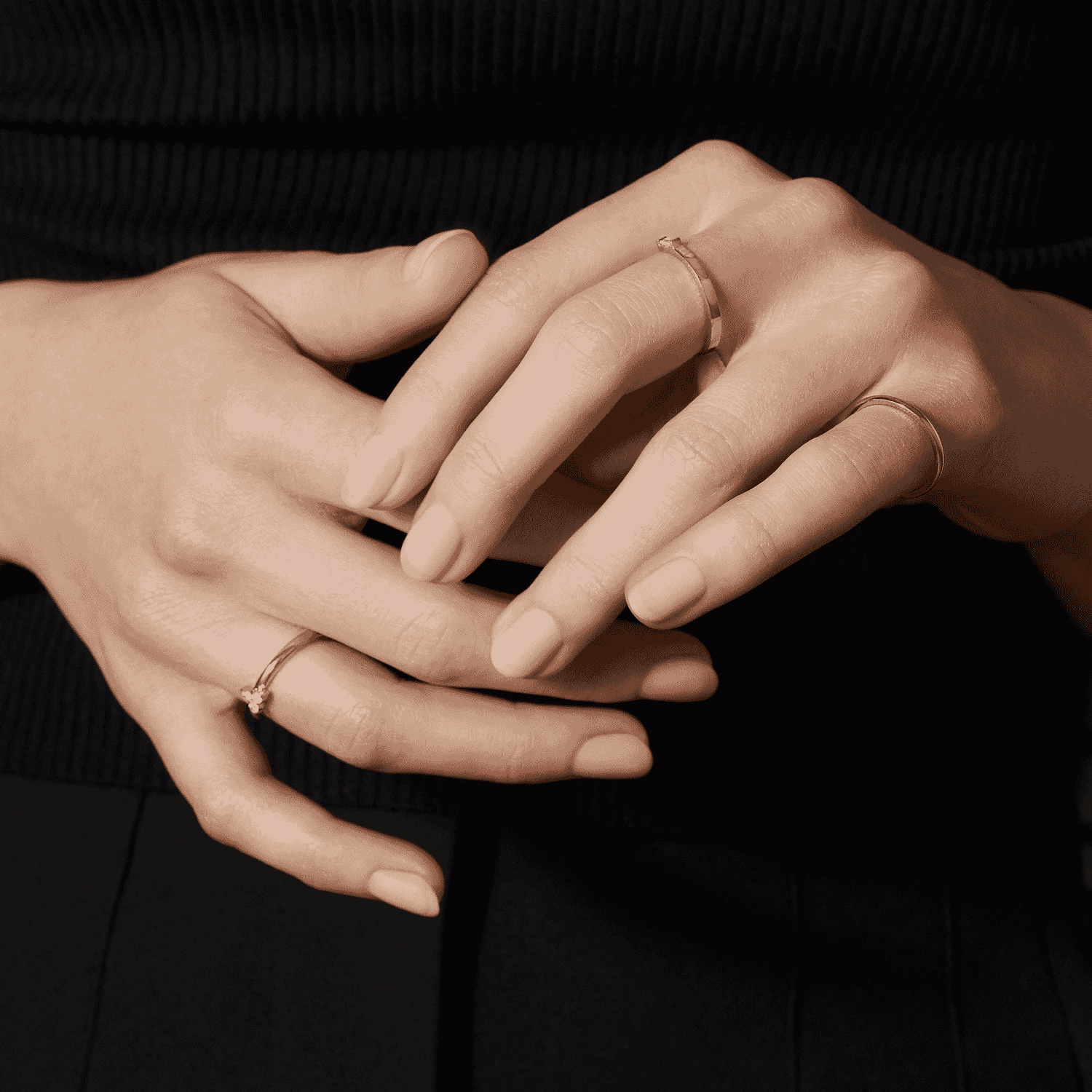Close-up of hands with minimalist gold rings on fingers, styled in a graceful pose