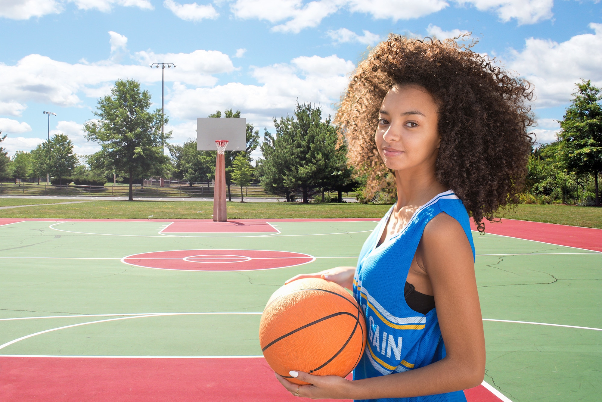 Retouched image of a female basketball player placed on a new outdoor court background after background removal and replacement.