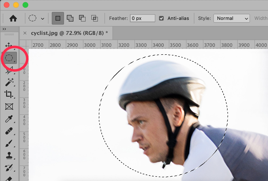 Photoshop 2025 showing the Elliptical Marquee Tool in use to select a circular area around a cyclist’s head for localized editing.