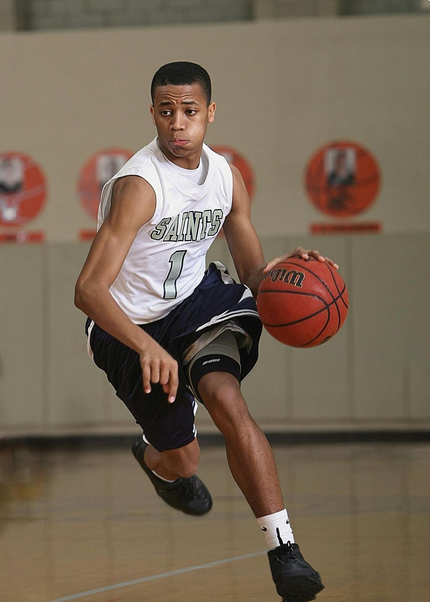 A basketball player in a gym, posing confidently with the ball, capturing strength and athleticism.