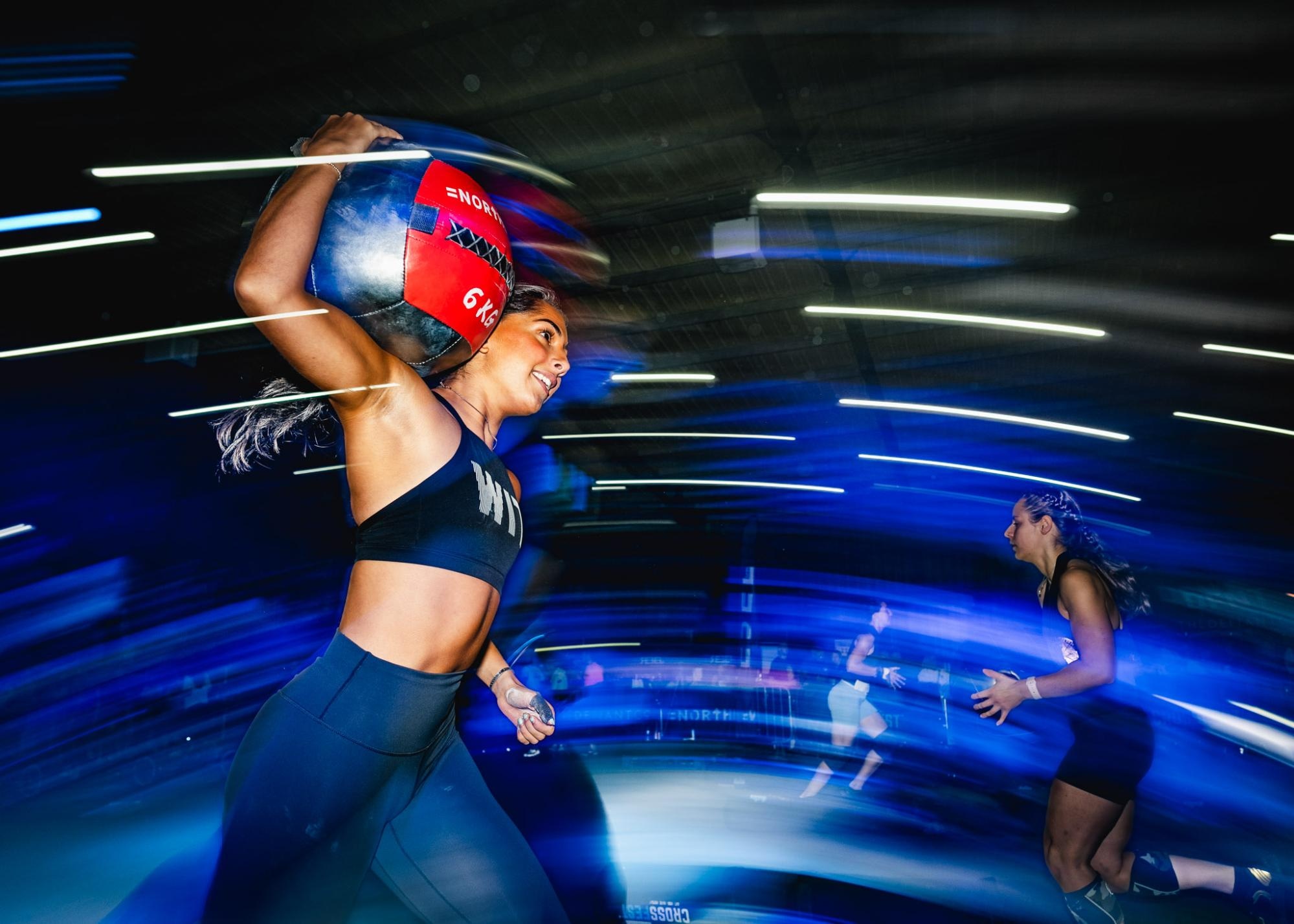 A female boxer in a boxing ring, illuminated by a spotlight, preparing to make a move with intense focus.