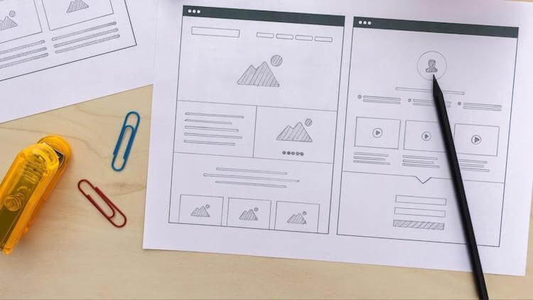 Printed website wireframe mockup with pen and paperclips for design planning