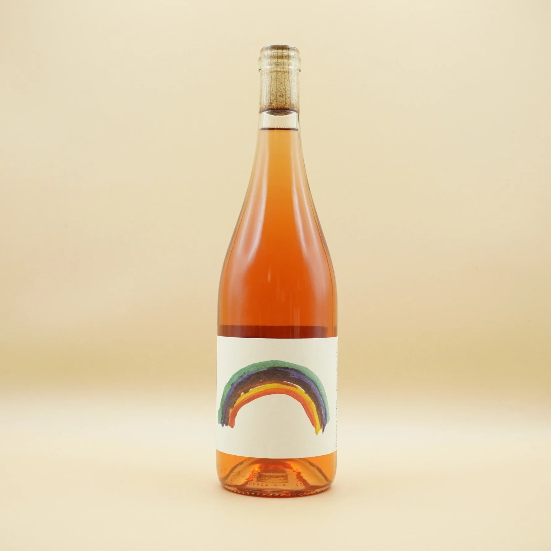 Rosé wine bottle with rainbow design on the label, set against a beige background.