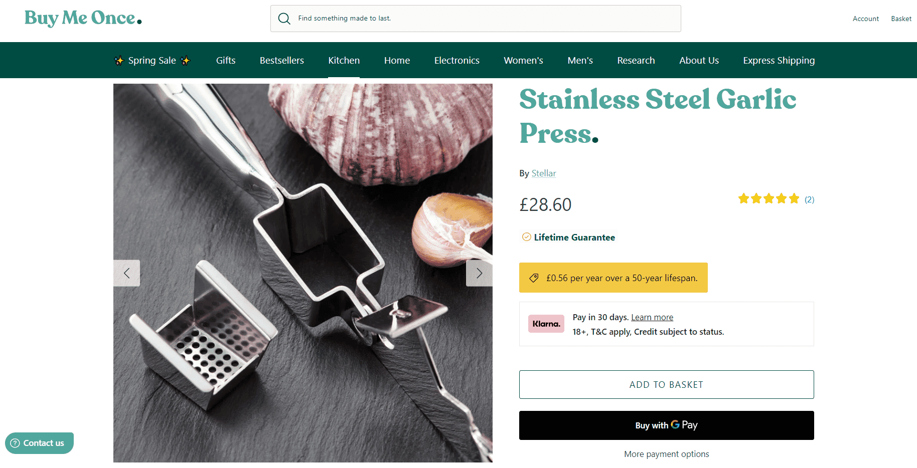 Stainless steel garlic press with garlic cloves on black surface, displayed on Buy Me Once product page.