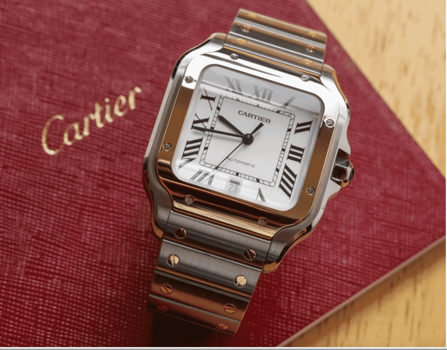 Cartier Santos watch with gold and steel bracelet displayed on red Cartier booklet