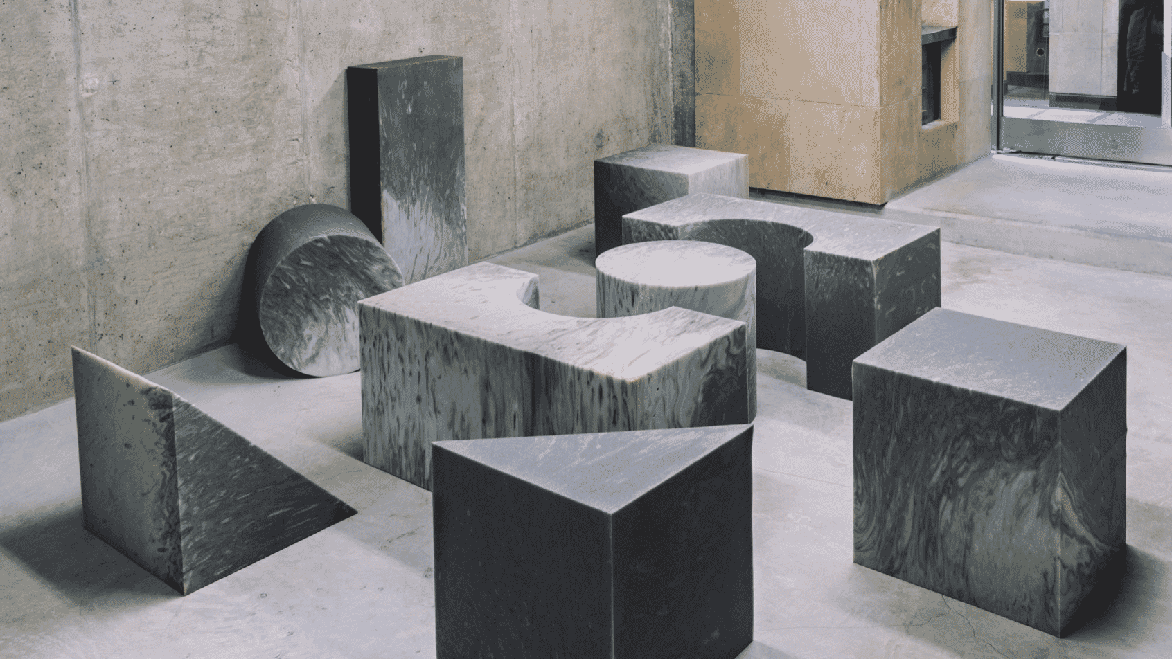 Various concrete geometric shapes arranged in an industrial-style room with textured walls