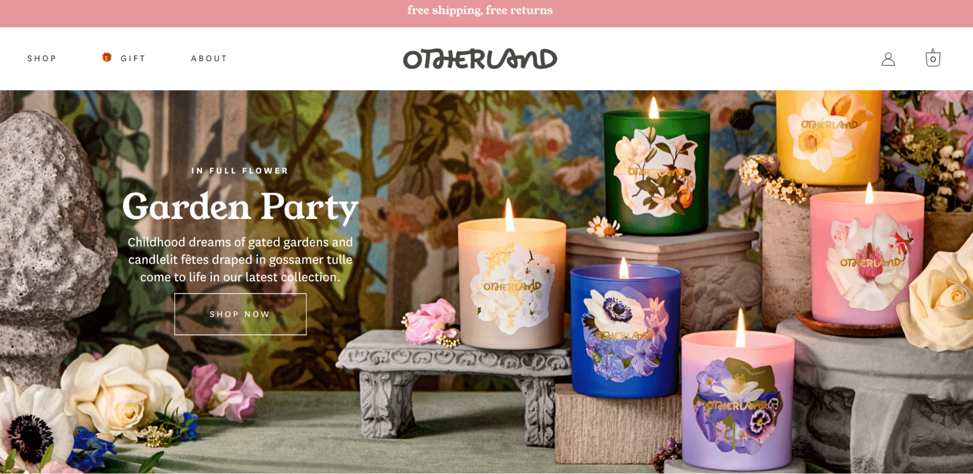 Colorful Otherland candles with floral designs arranged on stone and wood pedestals in a garden-inspired setting