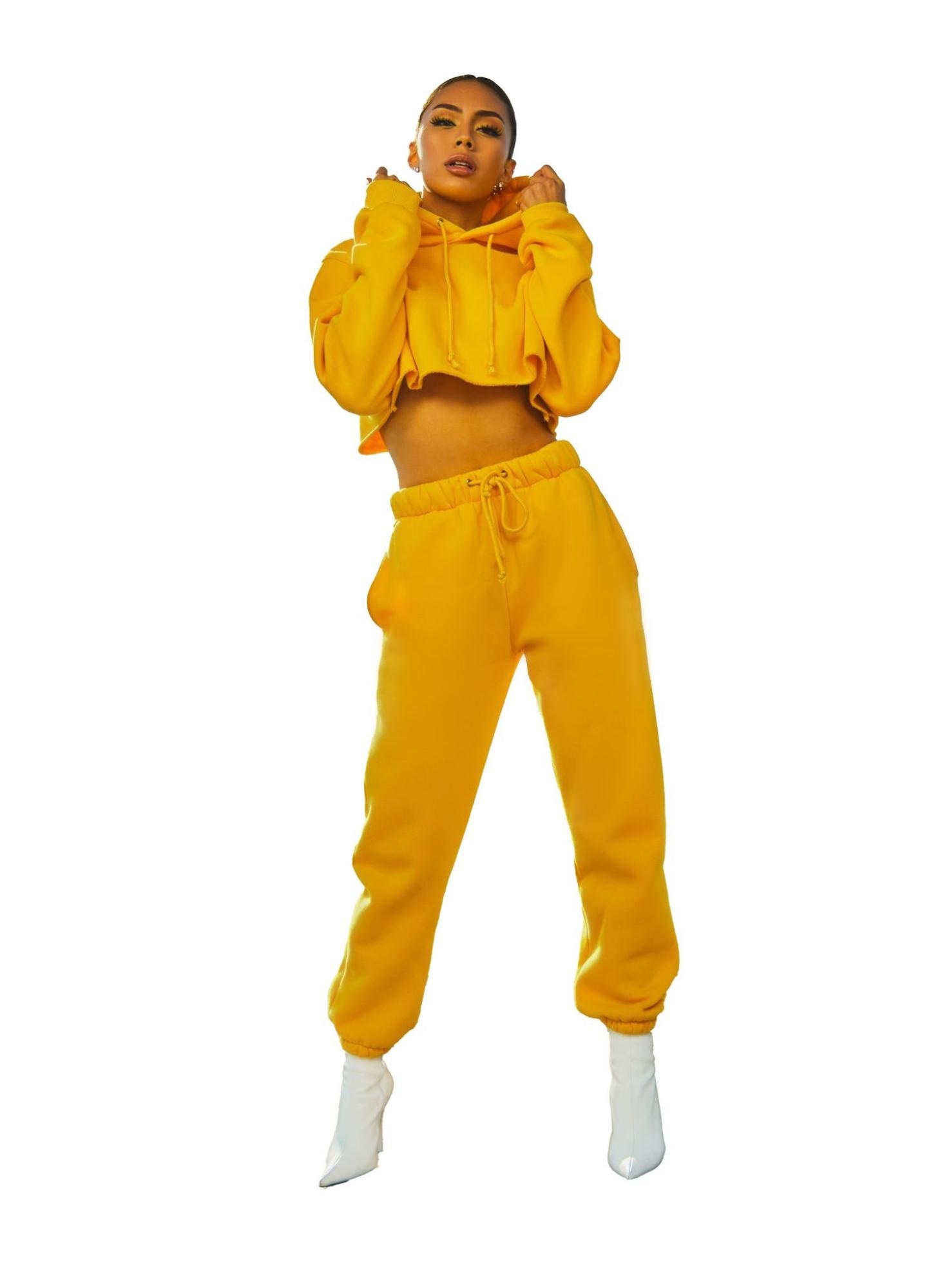 Model in yellow tracksuit against white background for retouch demonstration.