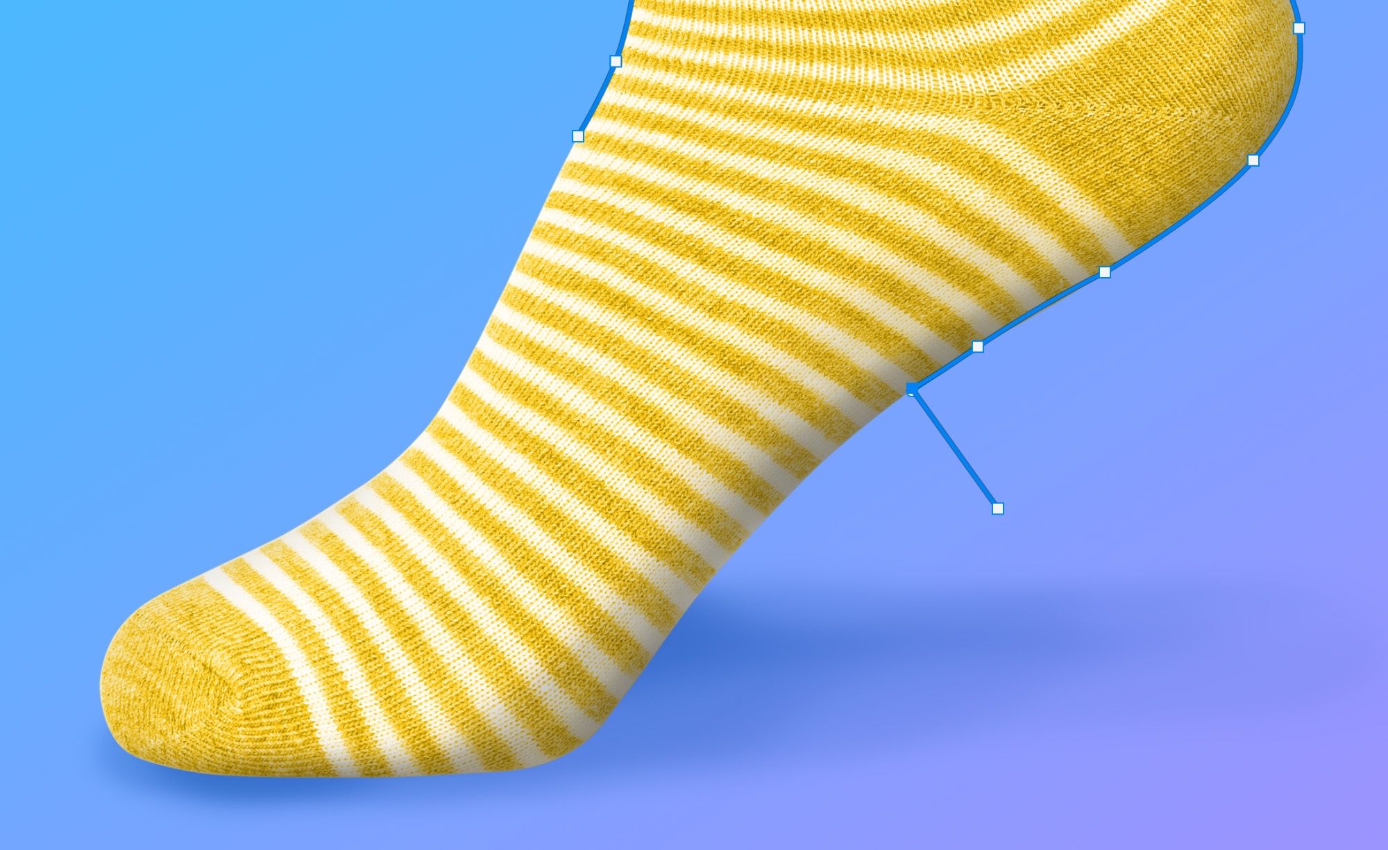 Photoshop Pen Tool precisely outlining the curved edge of a yellow striped sock on a blue gradient background for path creation.